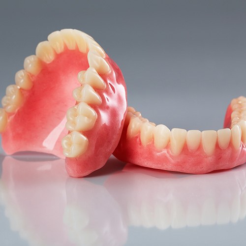 Set of dentures resting on a reflective gray surface