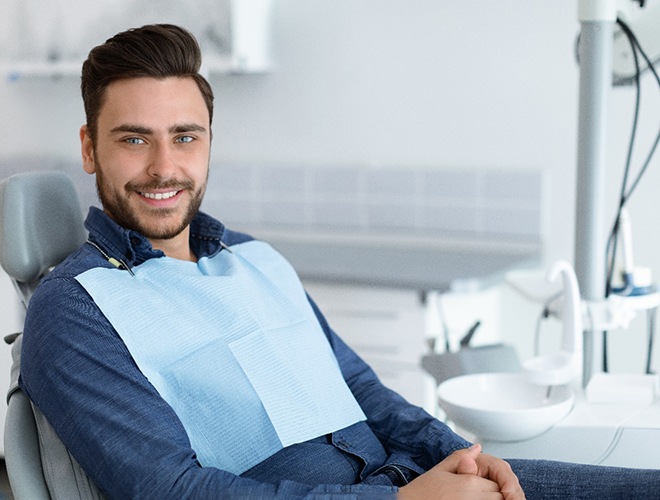 Man sitting in dental chair smiling after smile makeover in Midlothian, TX