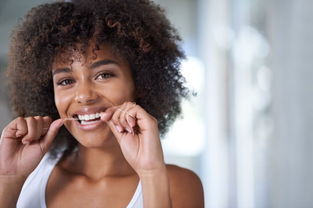 A woman flossing her teeth.