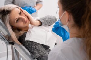 Woman holding face in the dentist's chair.
